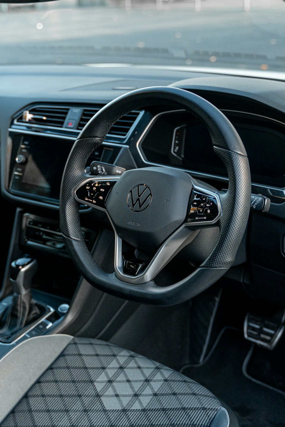 Buchung Moderner Autocockpit mit Lederlenkrad und kariertem Sitz.