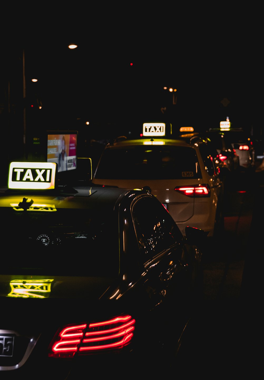 Dienstleistungen Taxis stehen nachts mit leuchtenden Schildern in einer Stadtstraße Schlange.