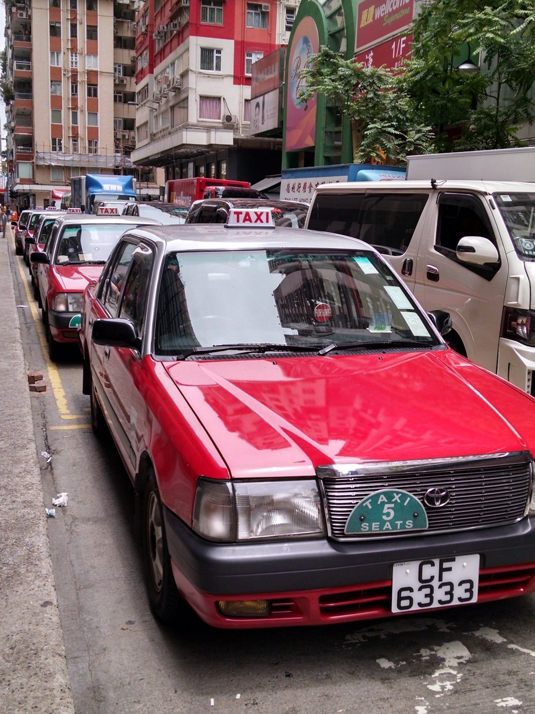 Rote und silberne Taxis warten auf einer Stadtstraße.